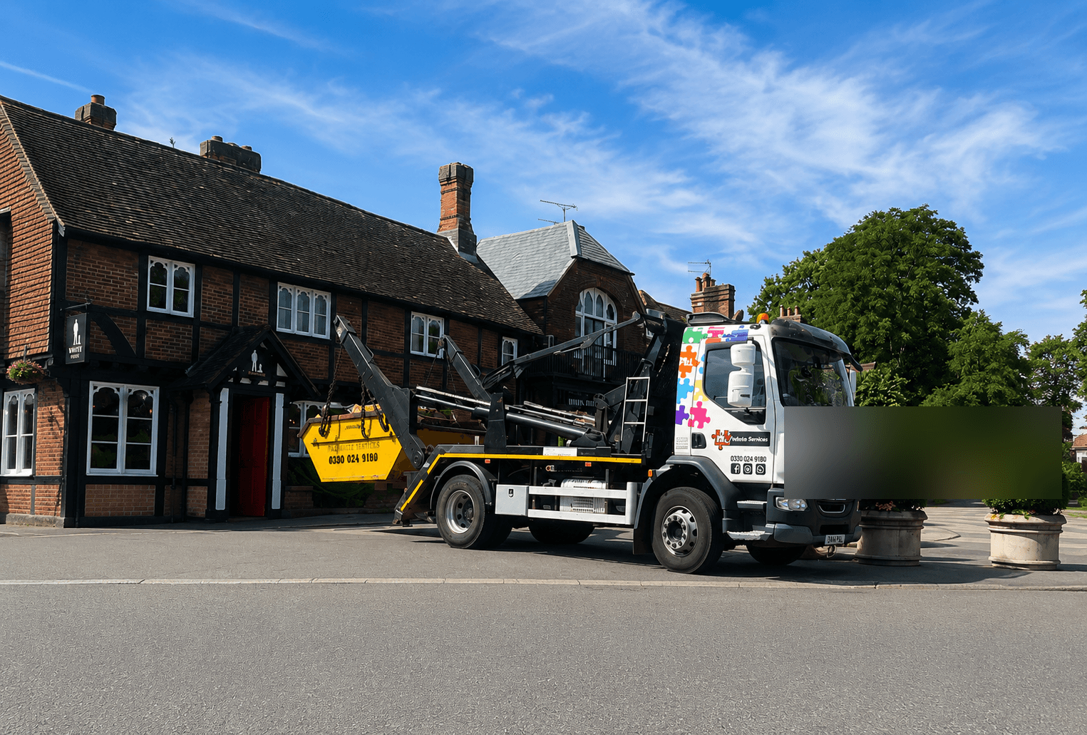FJL Waste Services lorry collecting a skip outside a row of period English cottages
