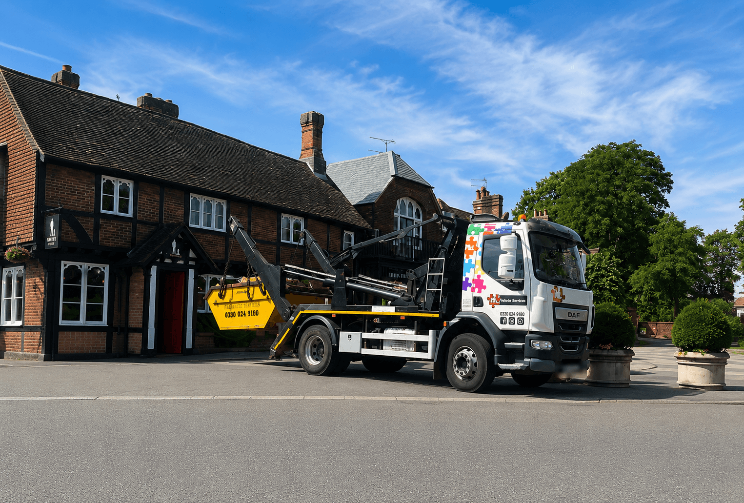 FJL Waste Services lorry collecting a skip outside a row of period English cottages